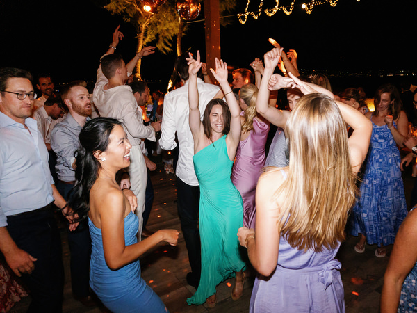 Guests dancing in circle at Island Resort, energetic Athens Riviera destination wedding reception.
