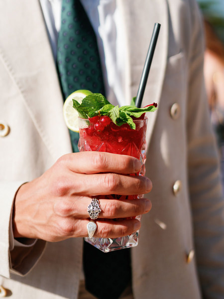 Close-up of wedding guest holding cocktail during luxury Cyprus resort wedding.