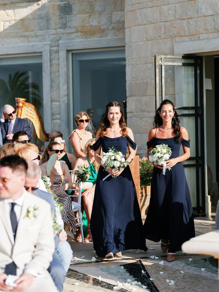 Bridesmaids walking down aisle at Anassa Hotel outdoor ceremony in Cyprus.