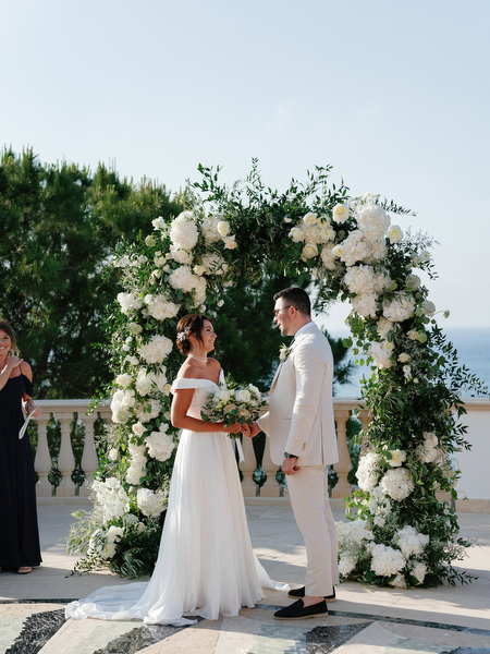 Bride and groom exchanging vows under floral arch at Anassa Hotel Cyprus.