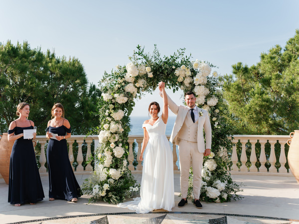 Newlyweds celebrating under floral arch at luxury Cyprus resort wedding.