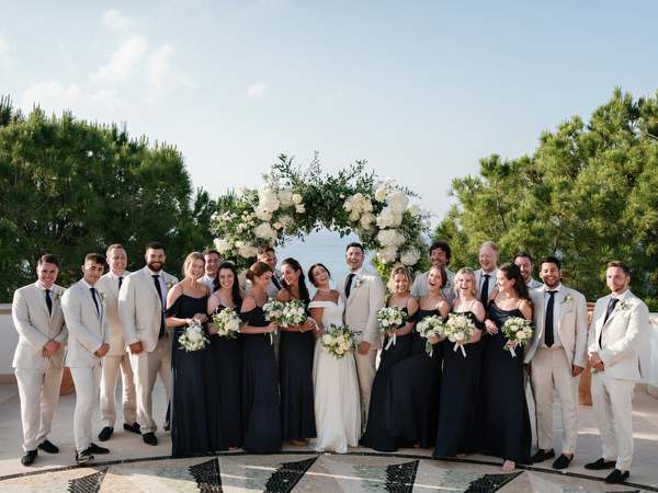 Bride, groom and wedding party posing at Anassa Hotel coastal ceremony.