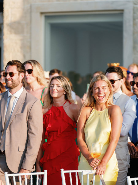 Wedding guests smiling during ceremony at Anassa Hotel Cyprus.