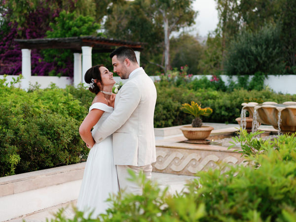 Bride and groom embracing in Mediterranean gardens at Anassa Hotel.