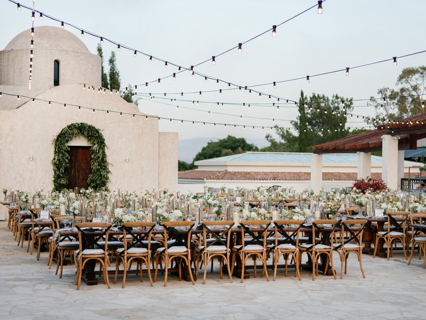 Long wooden dinner tables styled for luxury Cyprus wedding reception.