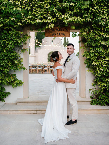 Bride and groom posing beneath ivy archway at Anassa Hotel Cyprus.