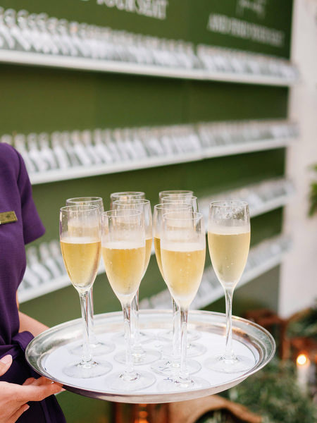 Champagne glasses on tray at escort card wall during Cyprus wedding reception.