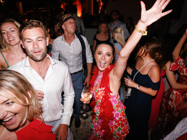 Group cheering with raised arms under night lights.