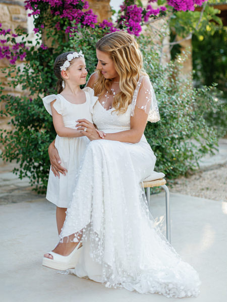 Bride holding flower girl during Antiparos wedding preparations.