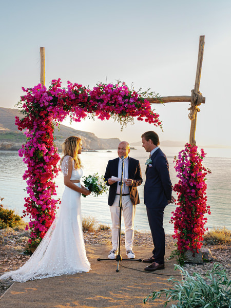 Bride and groom exchanging vows under bougainvillea arch in Antiparos.