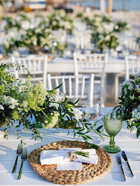 Wedding place setting with woven charger and greenery in Antiparos.