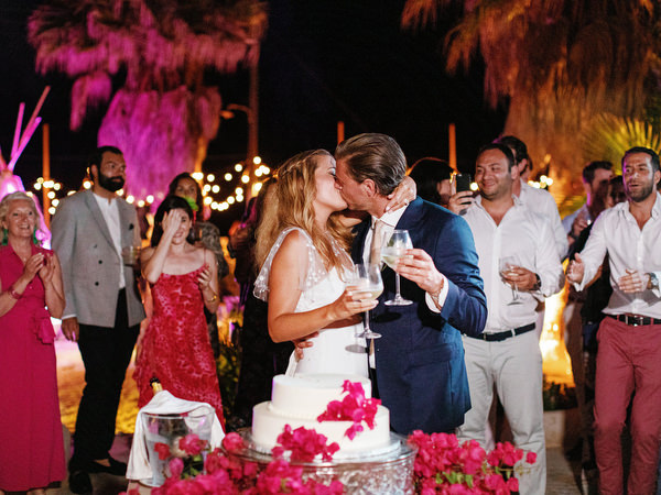 Bride and groom kissing after cutting wedding cake in Antiparos.