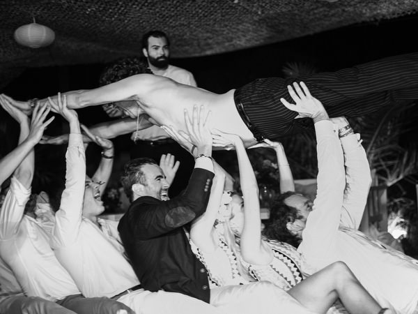 Groom lifted by friends during Antiparos wedding celebration.