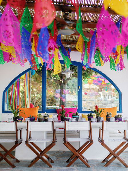Colorful papel picado banners at Mexican fiesta pre-wedding party in Antiparos