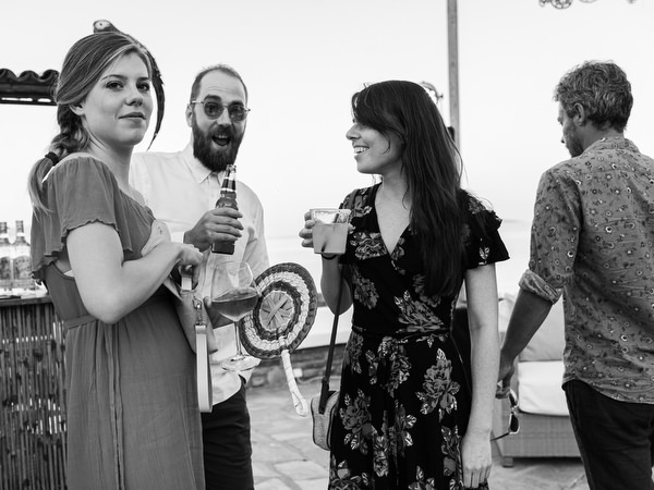 Black and White photo of guests chatting at Antiparos pre-wedding fiesta
