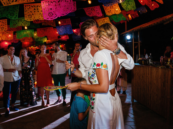 Couple kissing under colorful decorations at pre-wedding party