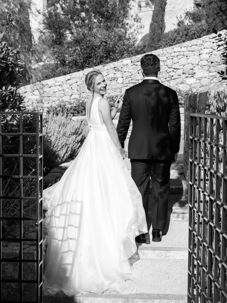 Bride and groom walking through Aria Estate courtyard in Greece