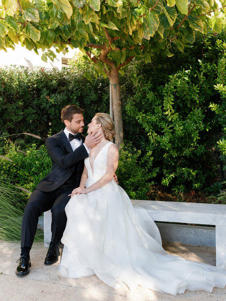Bride and groom seated under olive tree at Aria Estate wedding in the Peloponnese