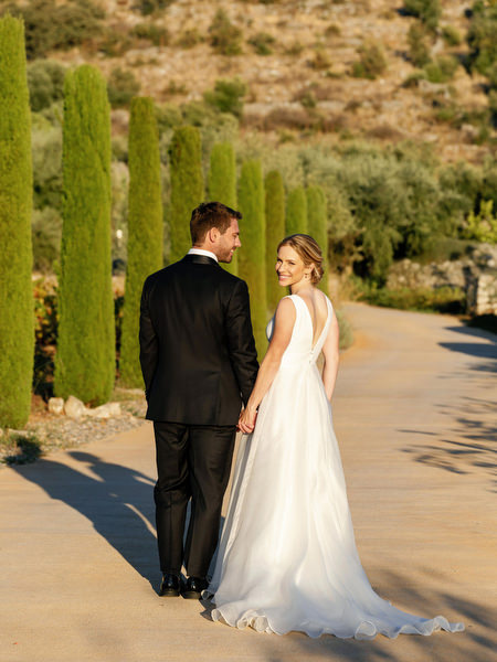 Bride and groom walking through Aria Estate grounds at sunset