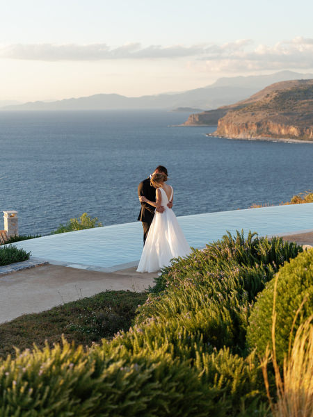 Bride and groom portrait by infinity pool at Aria Estate in Greece