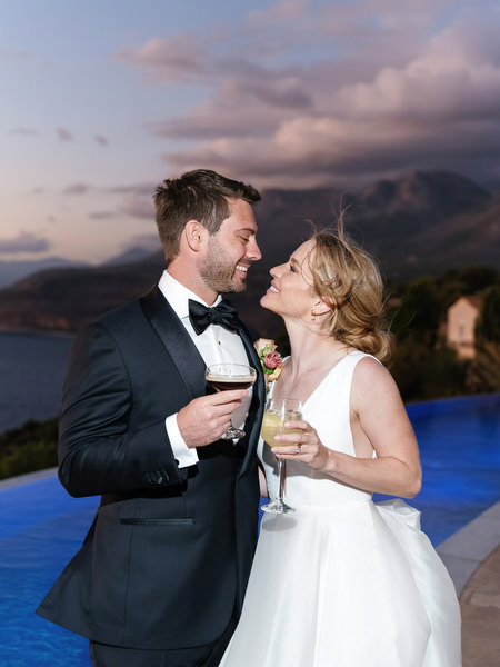 Bride and groom toasting at sunset at Aria Estate in Greece