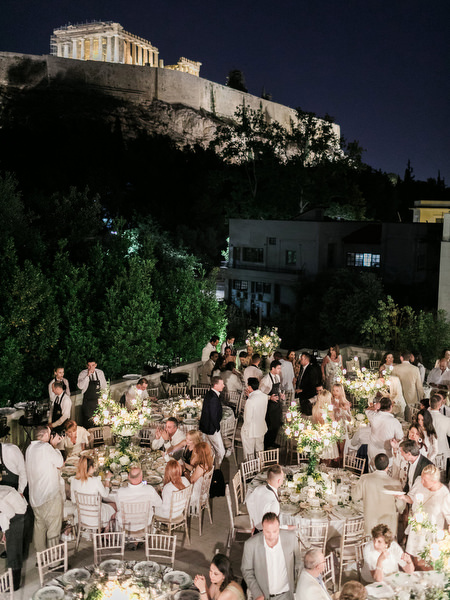 Nighttime pre-wedding dinner under the Acropolis with illuminated Parthenon