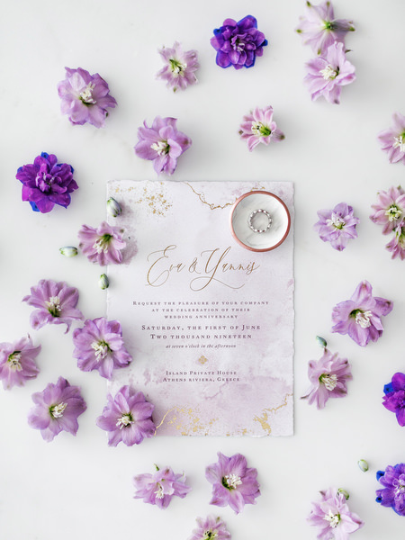 Wedding invitation surrounded by lilac blooms for a luxury destination wedding at Four Seasons Astir Palace on the Athens Riviera