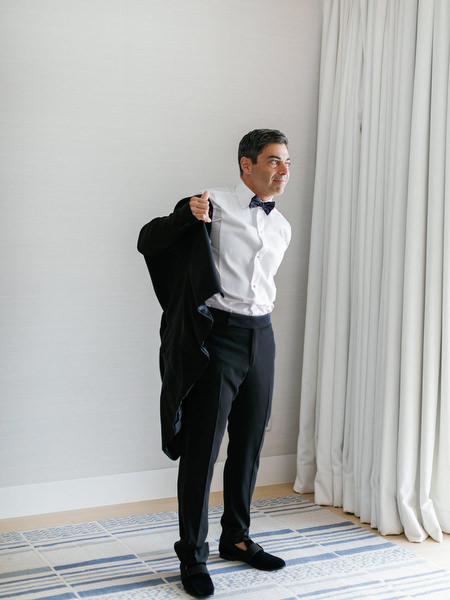 Groom putting on tuxedo jacket before the ceremony at Four Seasons Astir Palace during a refined Athens Riviera wedding