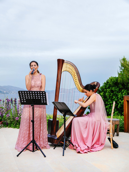 Live singer and harpist performing at an outdoor ceremony during an Athens Riviera wedding at Island Resort Athens Riviera, Greece