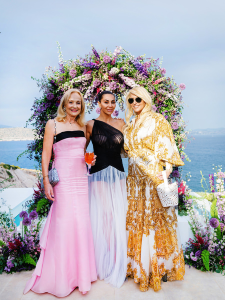 Guests posing beneath a sea-view floral arch during an Island Resort Athens Riviera Riviera wedding