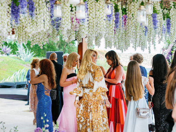 Guests mingling beneath hanging wisteria-inspired florals at an Athens Riviera wedding at Island Resort Athens Riviera