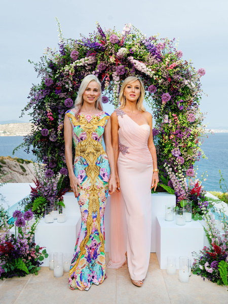 Guests posing beneath a floral ceremony arch overlooking the sea during an Athens wedding at Island Resort Athens Riviera