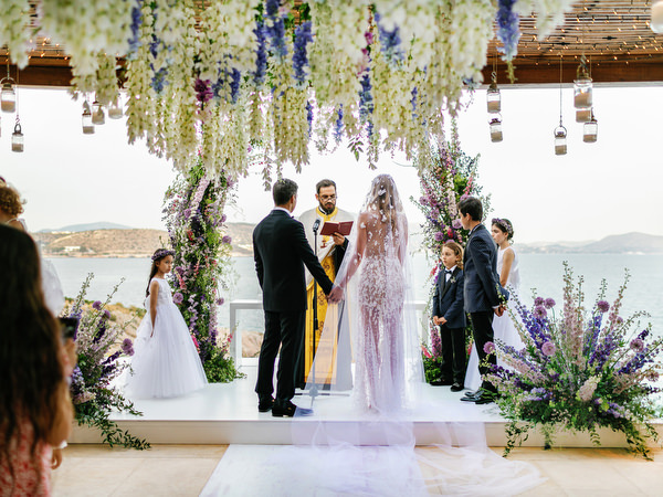 Bride and groom exchanging vows under hanging wisteria-inspired installations at an Island Resort Athens Riviera wedding