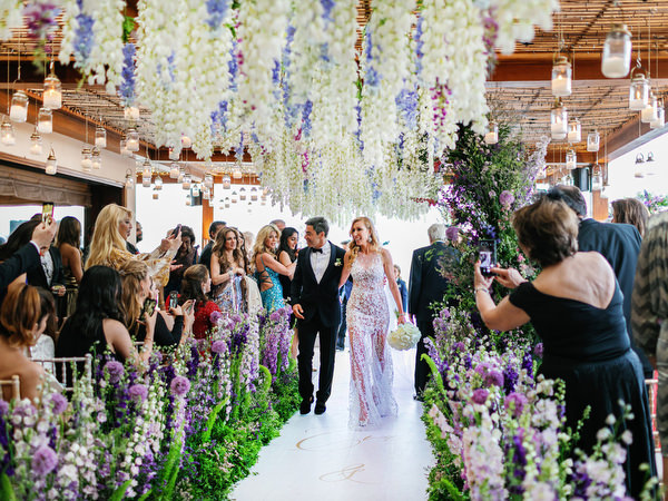 Bride and groom walking down a purple floral aisle during her Athens Riviera wedding at Island Resort Athens Riviera