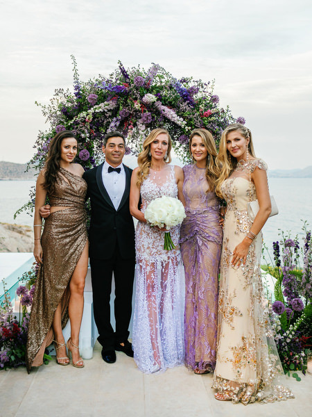Group portrait framed by lush purple florals at a destination Athens wedding at Island Resort Athens Riviera