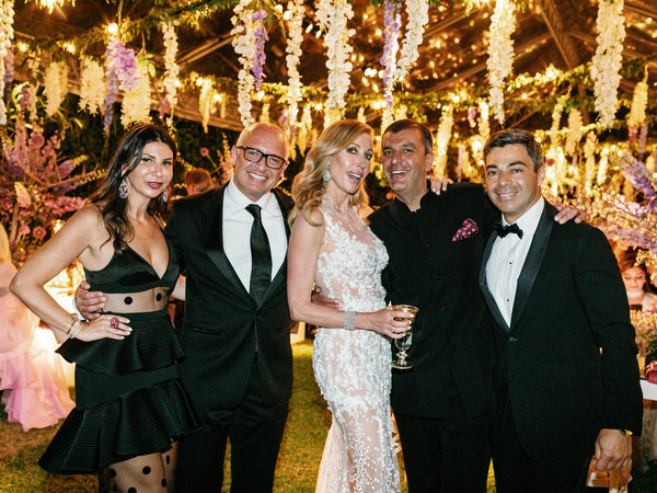 Couple posing with guests under glowing reception lights at a glamorous Athens wedding at Island Resort Athens Riviera