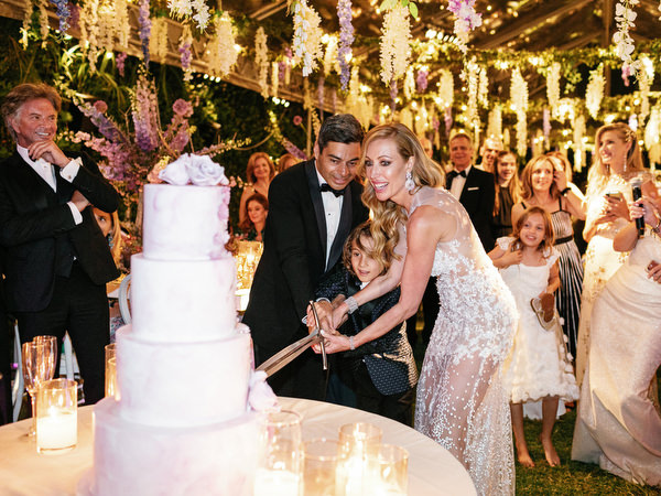 Bride and groom cutting their wedding cake beneath hanging florals at an Athens Riviera wedding at Island Art & Taste