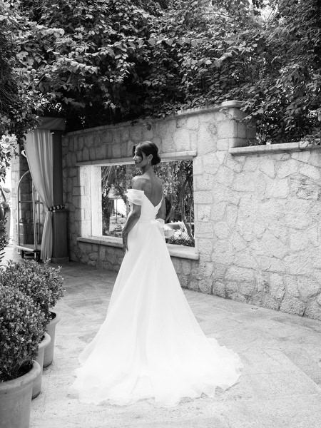 Bride standing beside stone wall at Margi Luxury Hotel before seaside ceremony