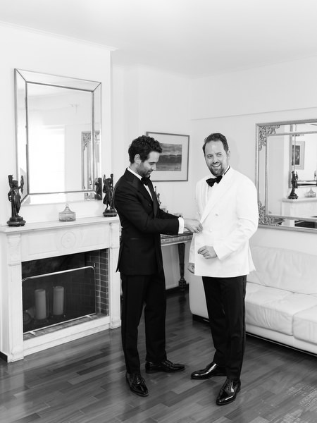 Groom adjusting white dinner jacket during elegant black-tie wedding morning in Athens