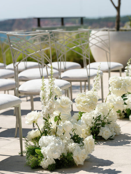 White floral arrangements and modern ceremony chairs set for black-tie wedding on the Athenian Riviera
