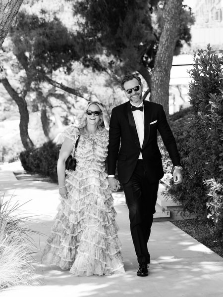 Guests in evening gowns and tuxedos walking through garden at Four Seasons Astir Palace Athens