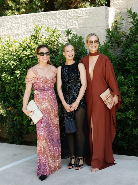 Guests in refined black-tie dresses posing before lakeside ceremony in Athens