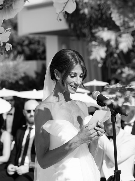 Bride smiling while reading vows at microphone during luxury Athens Riviera ceremony