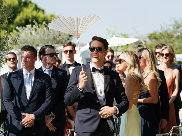 Guest smiling while holding white parasol among guests at Four Seasons Athens wedding