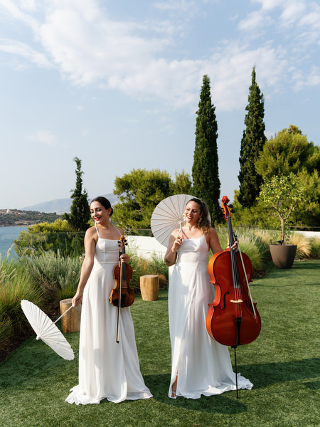 Violinist and cellist performing during outdoor ceremony on the Athenian Riviera