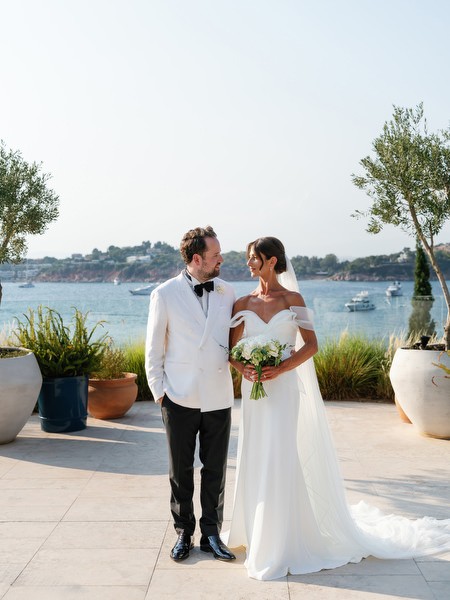 Bride and groom standing together with Mediterranean Sea in background at Athenian Riviera wedding