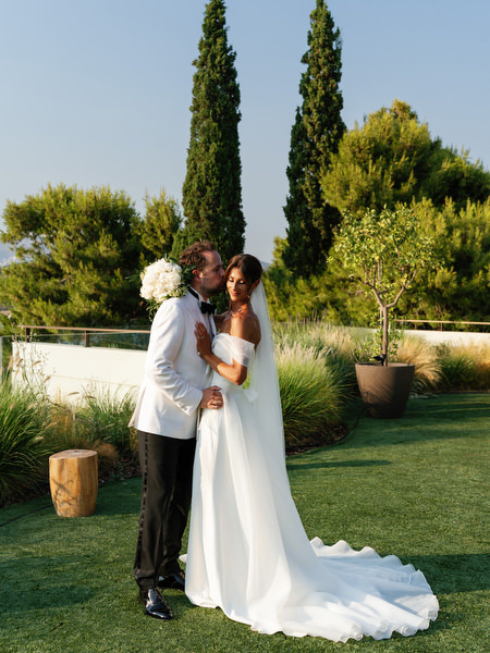 Bride and groom embracing on manicured lawn at Four Seasons Astir Palace Athens