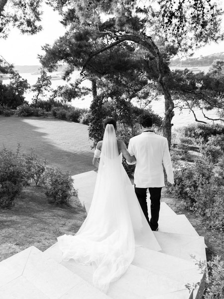 Bride and groom walking hand-in-hand through pine-lined path on the Athenian Riviera