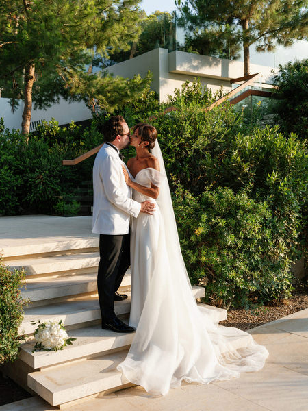 Bride and groom embracing on sunlit steps at Four Seasons Astir Palace Athens