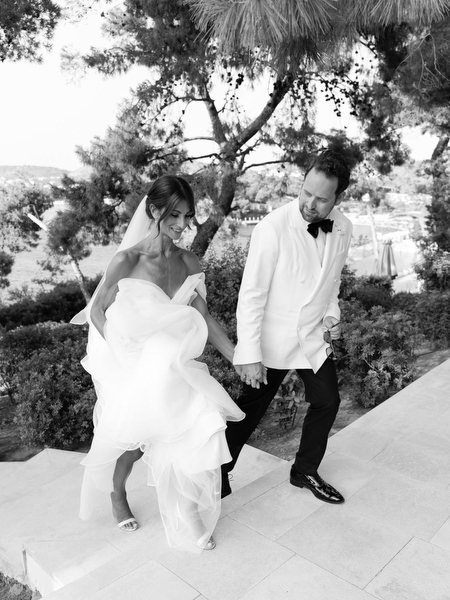 Bride and groom walking down resort steps during black-tie wedding at Four Seasons Astir Palace Athens